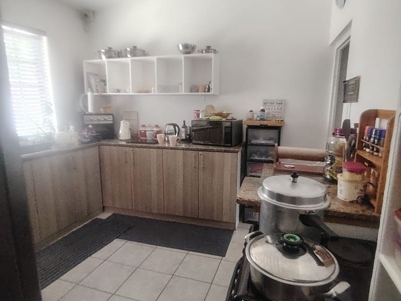 A functional kitchen featuring laminate cabinetry, granite countertops, and ceramic floor tiling with open shelving for storage.