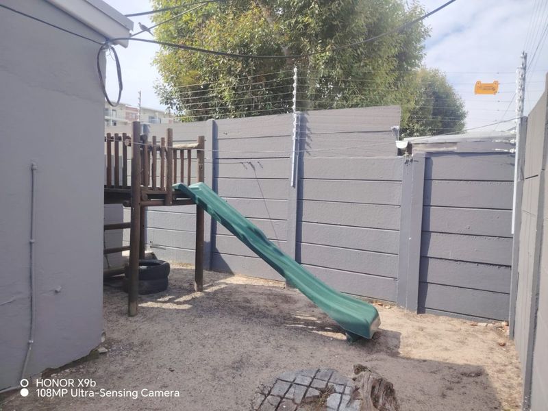 A rear outdoor area featuring a precast concrete boundary wall equipped with electric fencing.