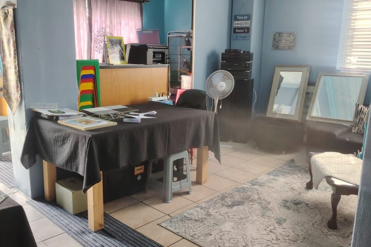 A multi-purpose living area featuring tiled flooring and blue painted walls, currently utilized as a workspace with basic structural finishes.