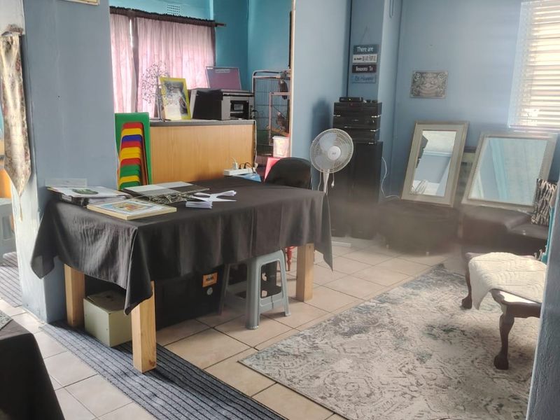 A multi-purpose living area featuring tiled flooring and blue painted walls, currently utilized as a workspace with basic structural finishes.