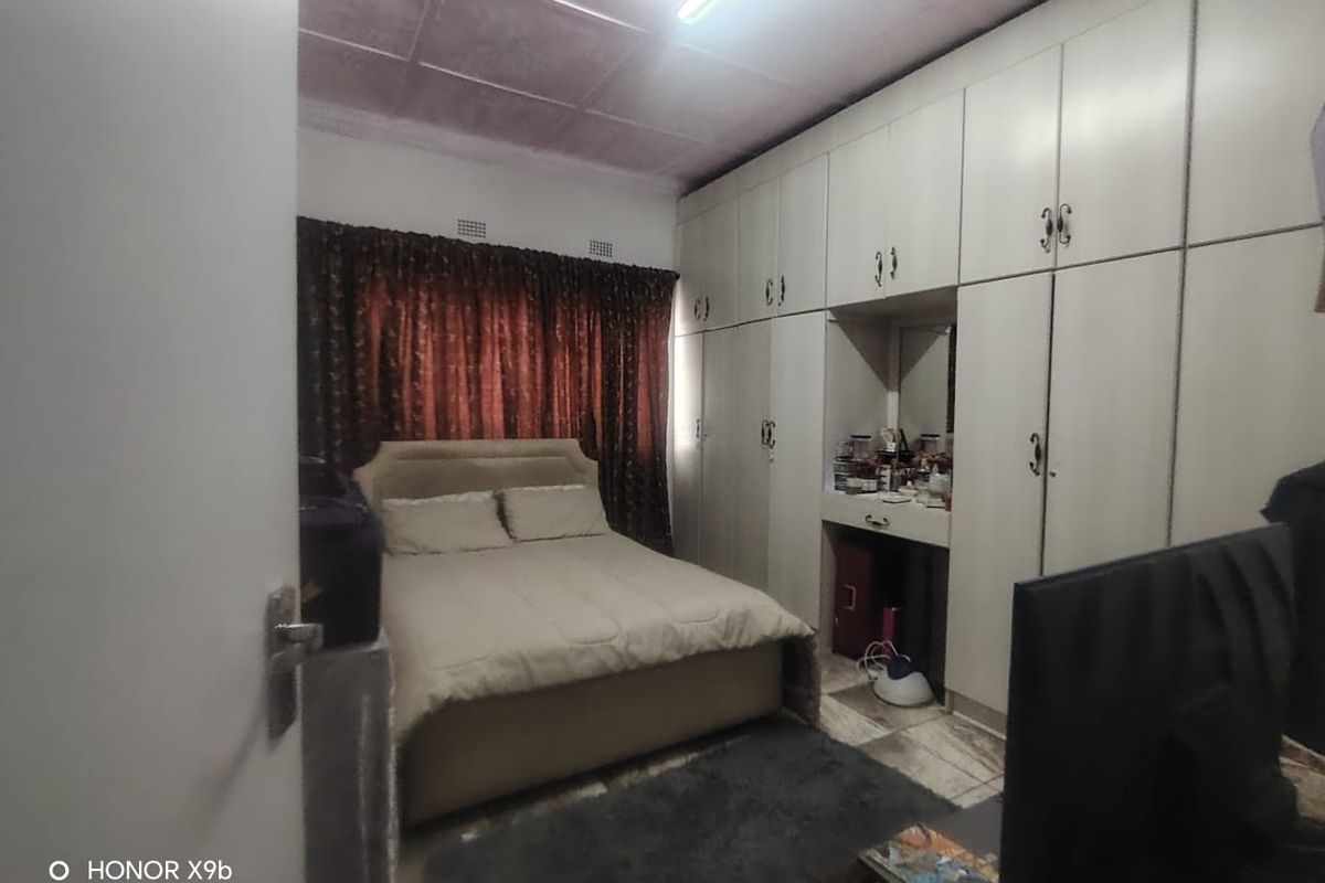 A bedroom featuring extensive built-in cupboards with an integrated vanity area and tiled flooring.