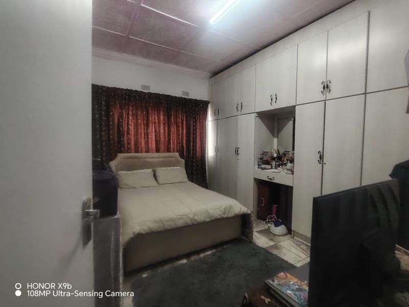 A bedroom featuring extensive built-in cupboards with an integrated vanity area and tiled flooring.