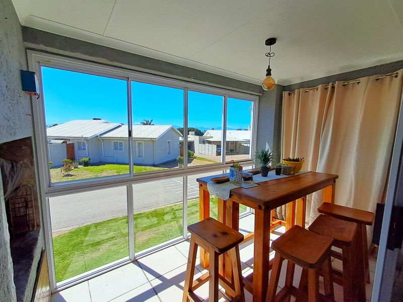 Enclosed patio area featuring large sliding glass windows, tiled flooring, and a built-in fireplace, offering a bright and versatile space for relaxation.