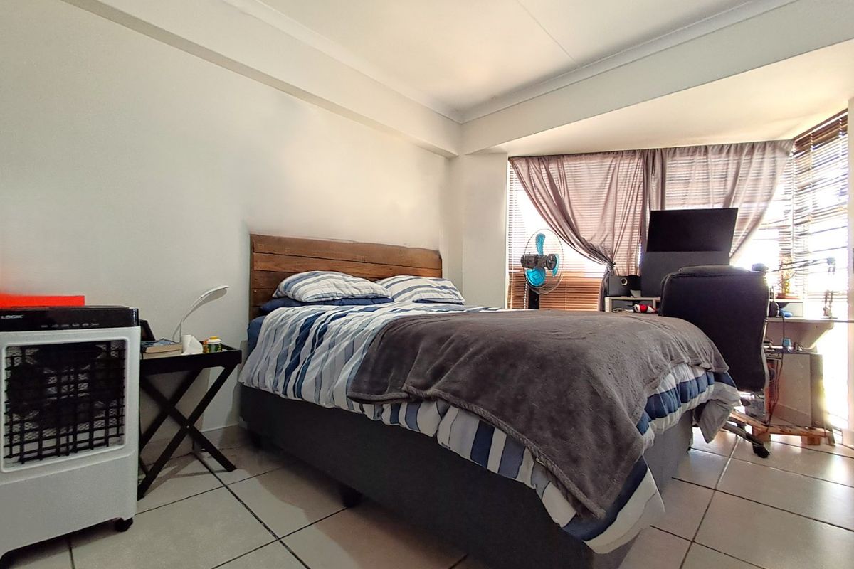 A bedroom featuring tiled flooring and cove cornice detailing, with large windows allowing for natural light.