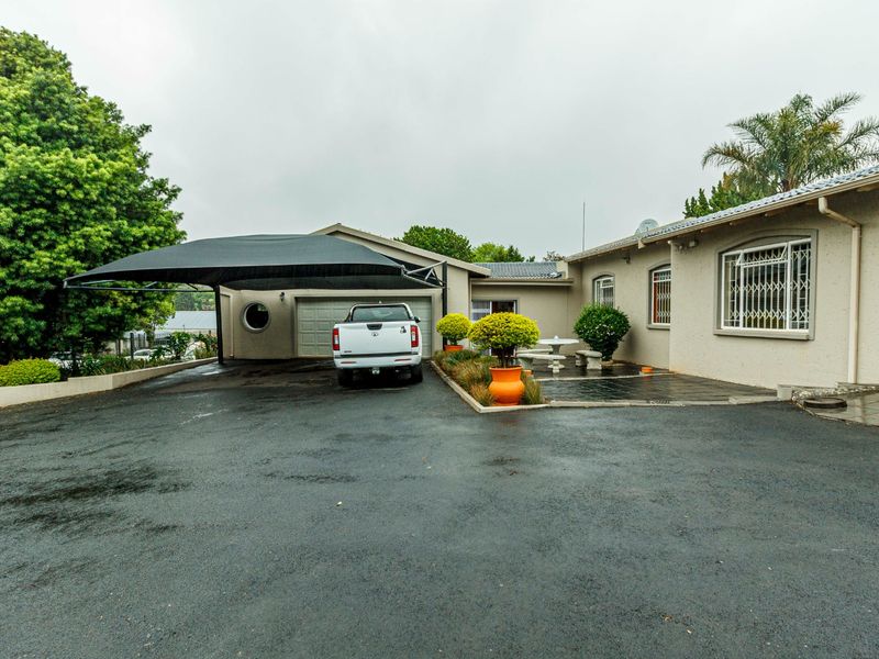 Front exterior view of the house featuring a paved driveway, shadeport, garage, and security-fitted windows.