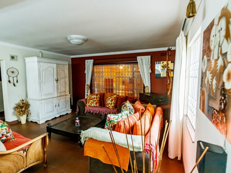 A living room featuring tiled flooring, coving, and window blinds, providing a functional space with potential for modern updates.