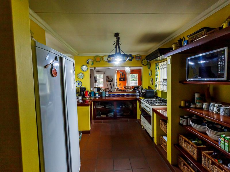A functional kitchen featuring tiled flooring, built-in cabinetry, gas stove with extractor, and tiled countertops, with an open-plan layout leading to the living area.