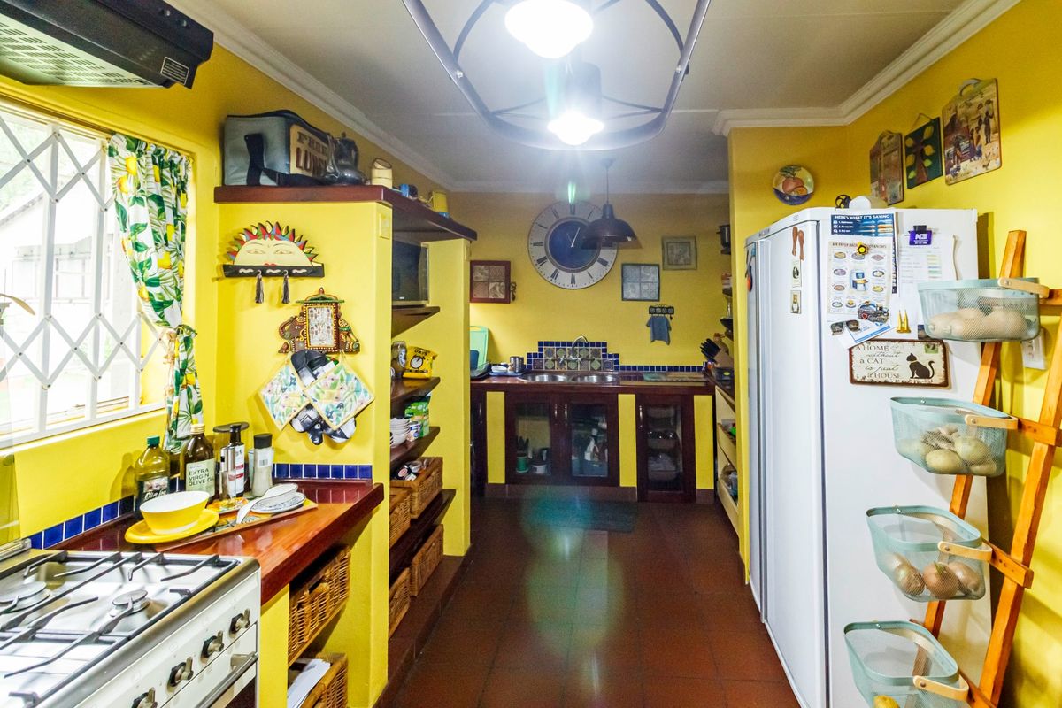 A functional kitchen featuring a gas stove, extractor fan, built-in cabinetry, and tiled flooring with a classic layout.