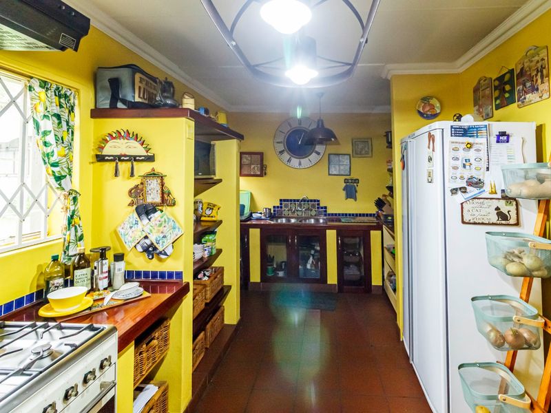 A functional kitchen featuring a gas stove, extractor fan, built-in cabinetry, and tiled flooring with a classic layout.