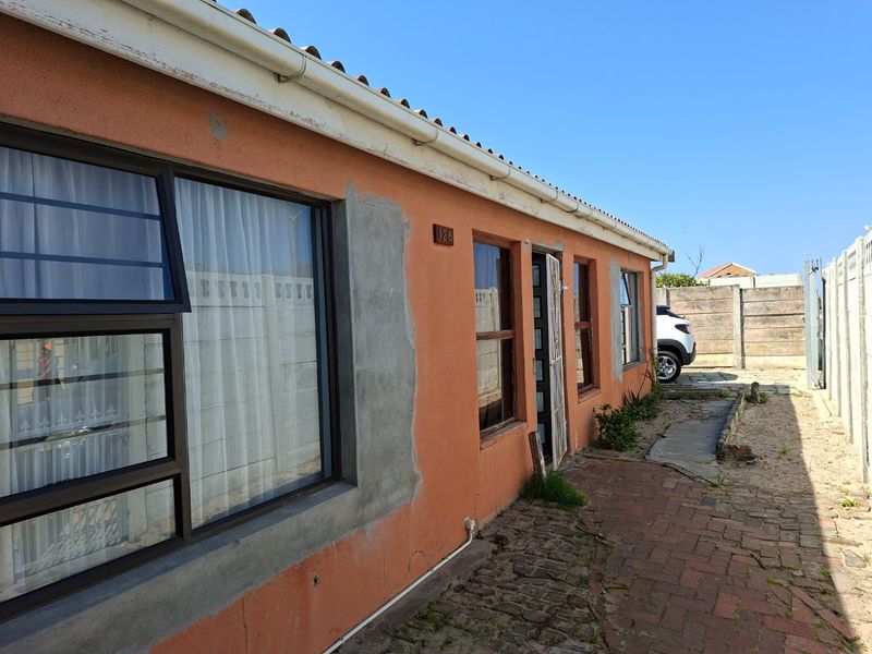 Rear exterior view of the house featuring brick paving, precast boundary walls, and unfinished plasterwork on the exterior facade.