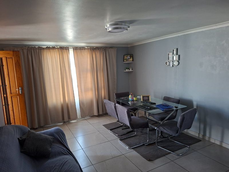 A dining area featuring tiled flooring and neutral wall tones, providing a functional space for meals with natural light from the window.