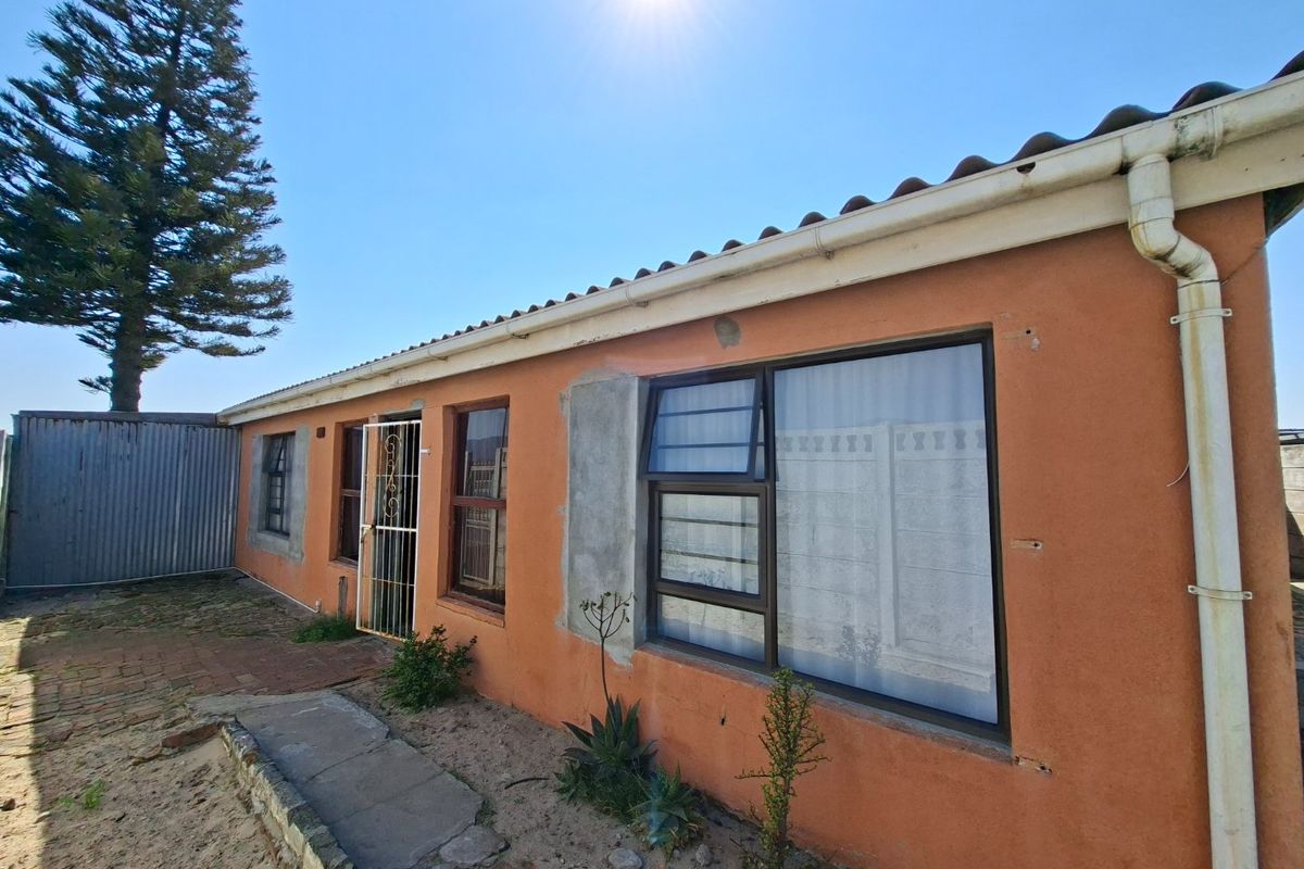 Rear exterior view of the property featuring a tiled roof, aluminium window frames, and a paved walkway along the building facade.