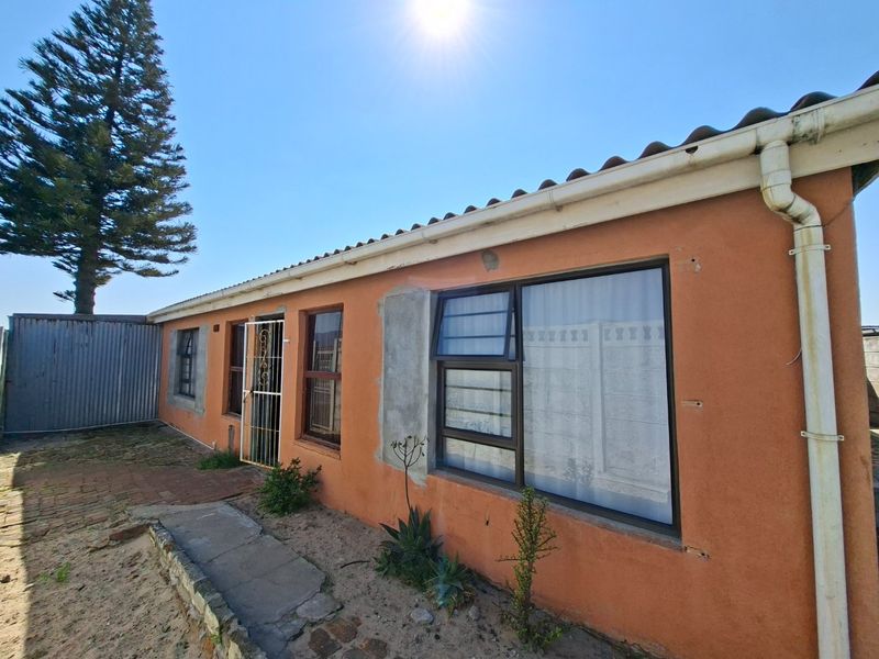 Rear exterior view of the property featuring a tiled roof, aluminium window frames, and a paved walkway along the building facade.