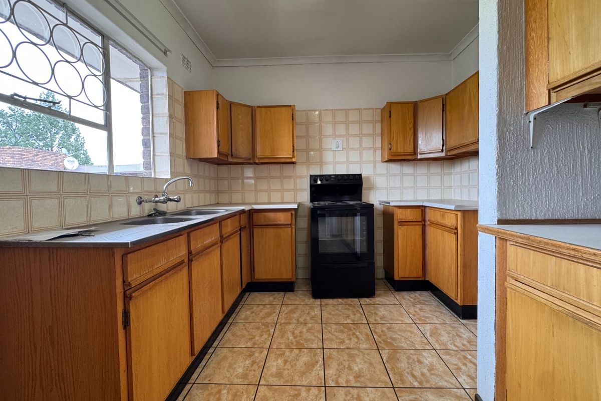 A functional kitchen featuring wooden cabinetry, tiled backsplash, and a freestanding stove, offering a blank canvas for modern renovation and design updates.