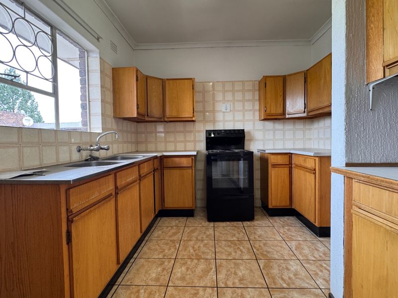 A functional kitchen featuring wooden cabinetry, tiled backsplash, and a freestanding stove, offering a blank canvas for modern renovation and design updates.