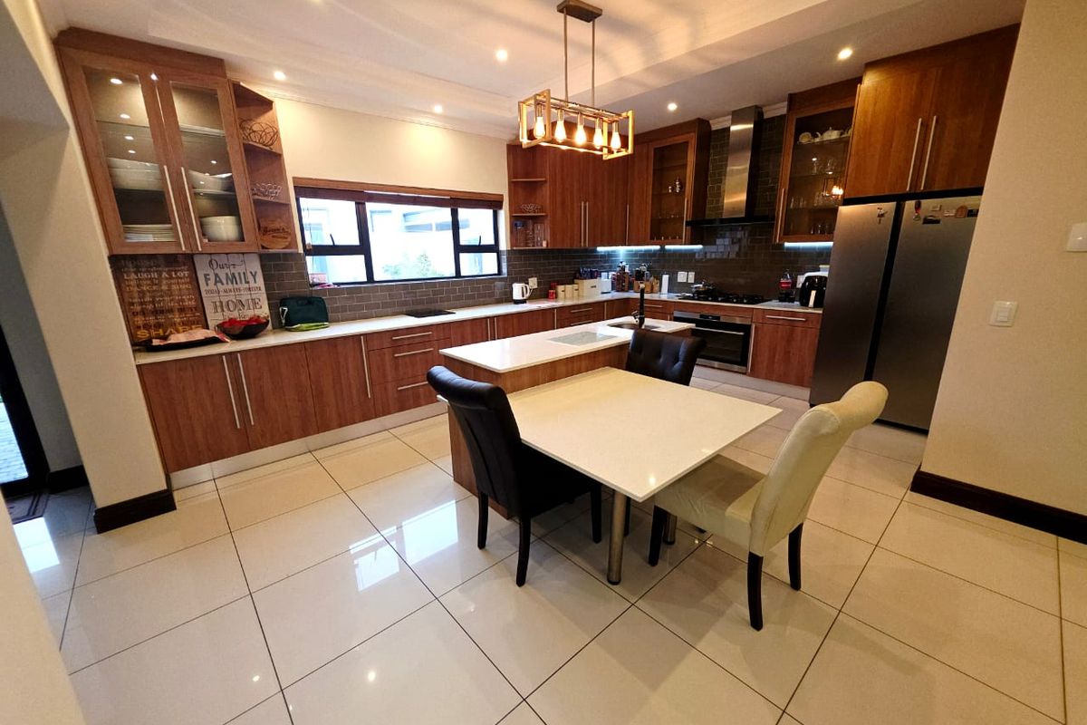 Modern kitchen featuring wood-finish cabinetry, stone countertops, a central island, integrated appliances, and stylish subway tile backsplash with recessed lighting.