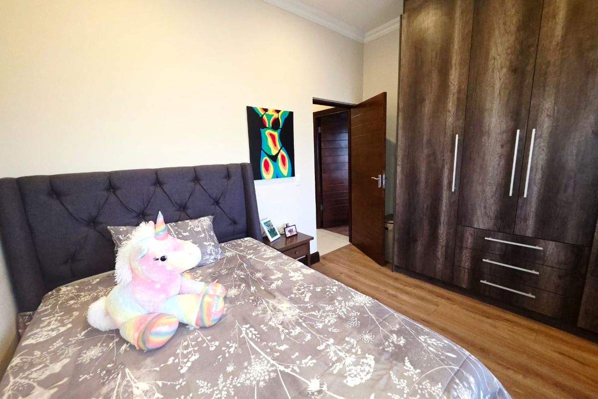 A well-maintained bedroom featuring laminate flooring, built-in dark wood cupboards, and decorative coving.