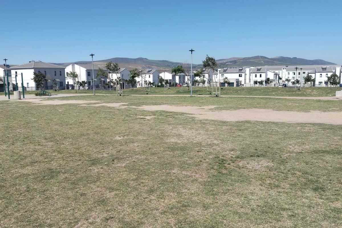 A wide-angle view of a communal green space and lawn area situated within a residential housing estate.