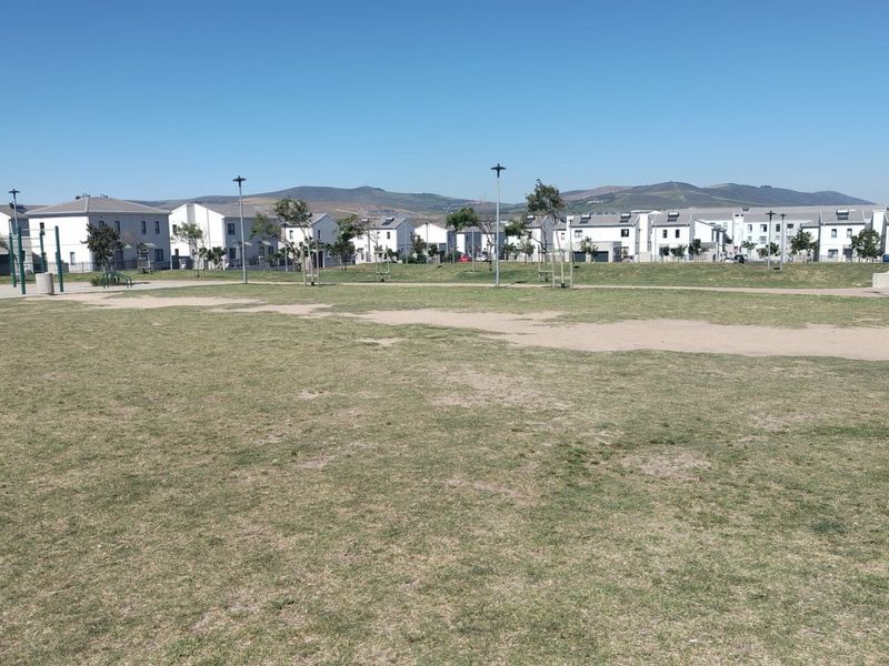 A wide-angle view of a communal green space and lawn area situated within a residential housing estate.