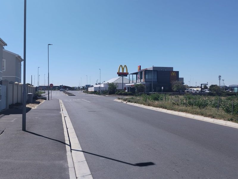 A view of the street approach showing the surrounding neighbourhood infrastructure and nearby commercial amenities.