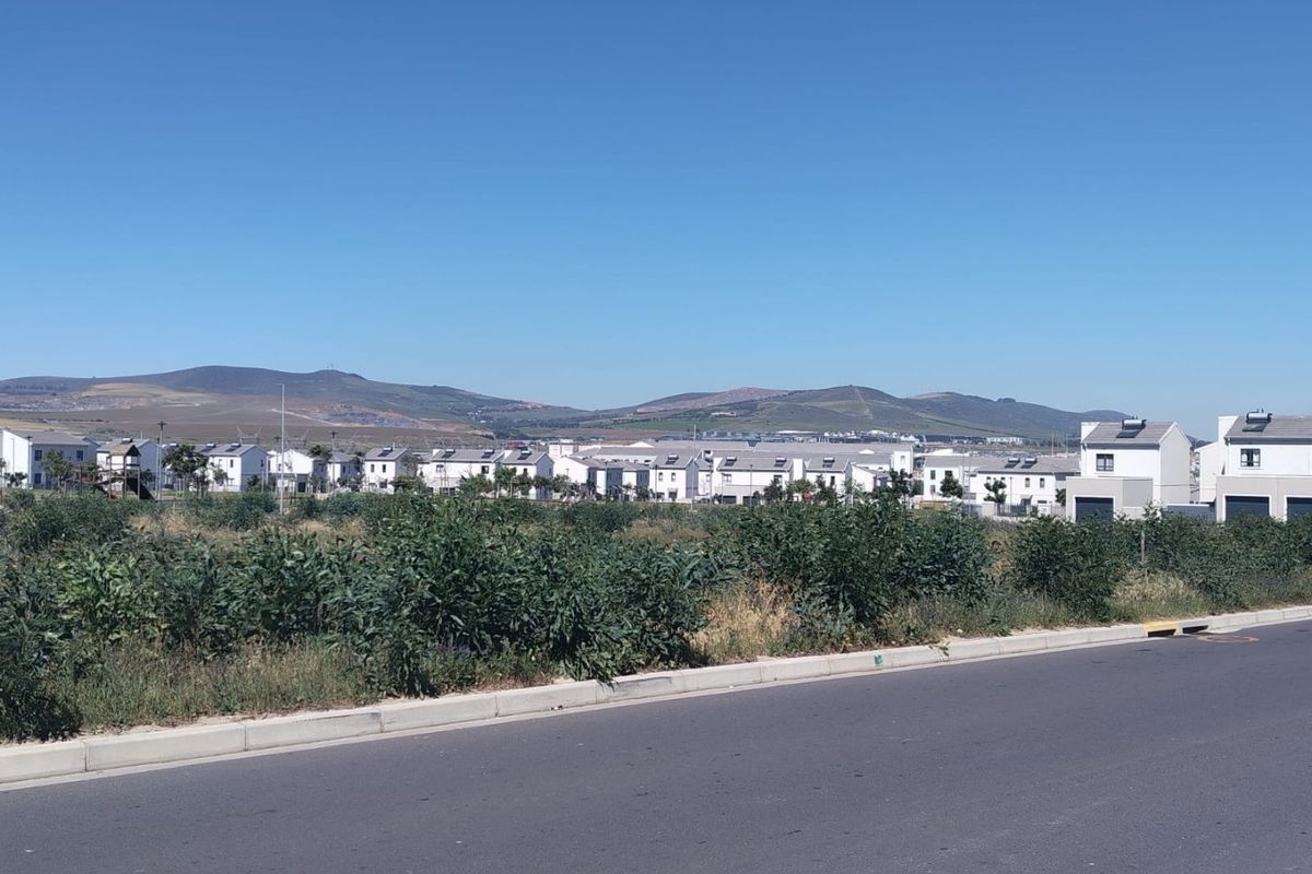 A street-level view of a residential housing development with mountain vistas in the background.