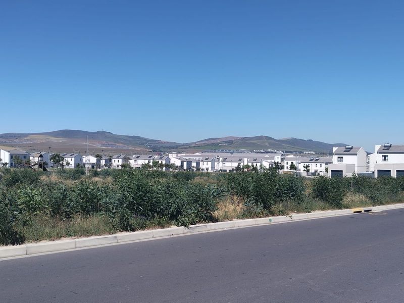 A street-level view of a residential housing development with mountain vistas in the background.