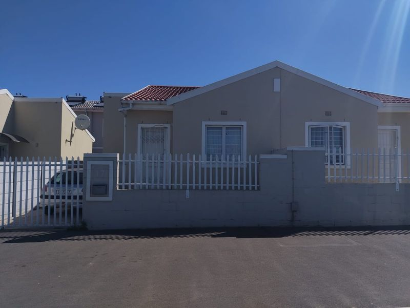 Front elevation of a single-story house featuring a tiled roof, perimeter wall with metal fencing, and security fixtures on windows and doors.
