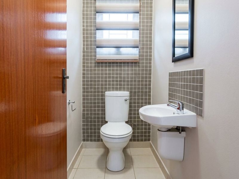 A compact guest bathroom featuring a wall-mounted basin, modern toilet, and neutral tiled finishes.