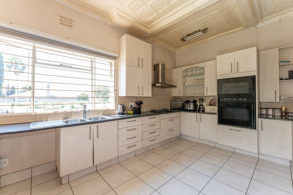 A functional kitchen featuring built-in cabinetry, a gas hob, integrated oven, double sink, and decorative ceiling detail with tiled flooring throughout.