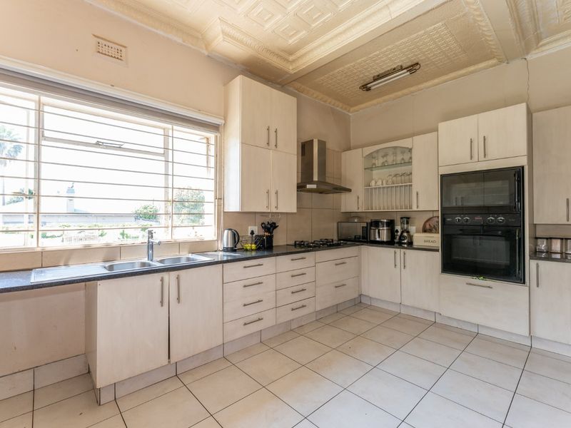 A functional kitchen featuring built-in cabinetry, a gas hob, integrated oven, double sink, and decorative ceiling detail with tiled flooring throughout.