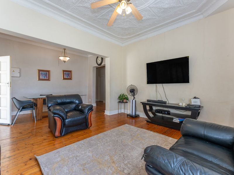 Open plan living and dining area featuring original pressed metal ceilings, hardwood flooring, and a ceiling fan.