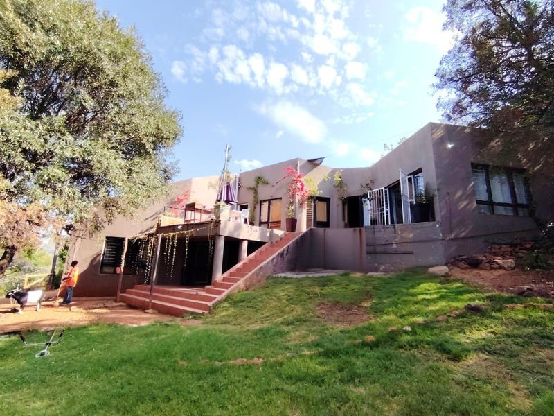 Rear view of the farm property featuring a raised patio, concrete staircase, and large windows overlooking the garden area.