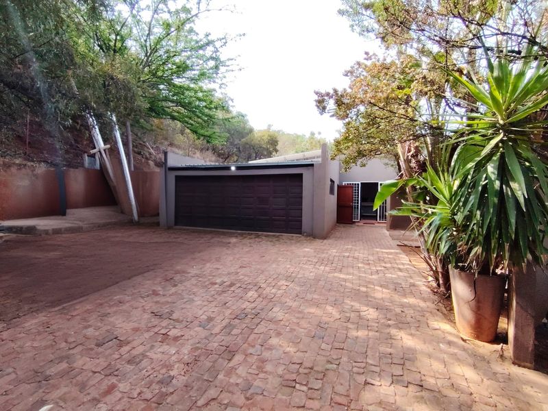 Exterior view of a garage with a sectional door, featuring a brick-paved driveway and surrounding landscaped garden area.