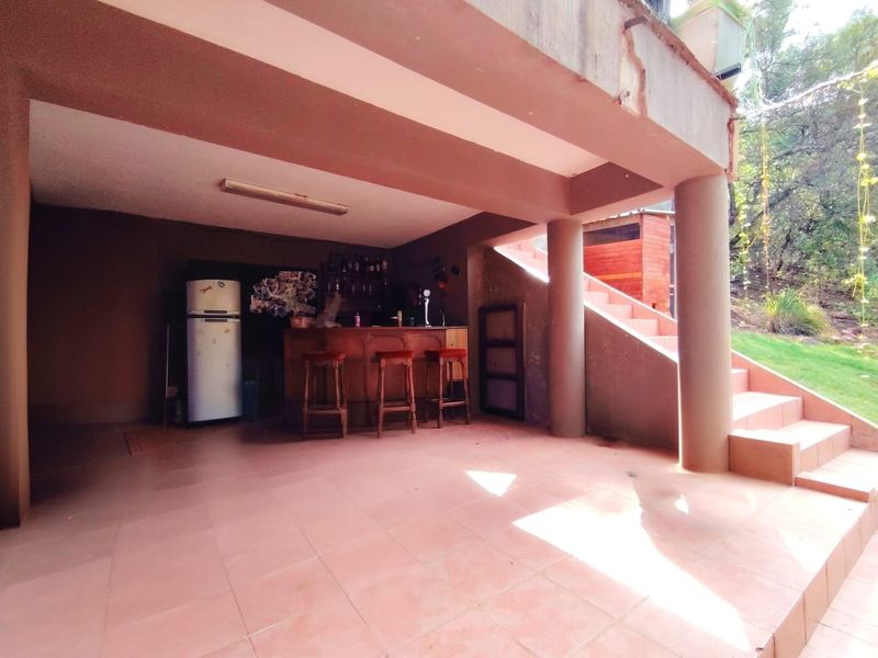 Covered outdoor patio area featuring a built-in bar, tiled flooring, and concrete structural columns, providing a functional space for outdoor entertainment.