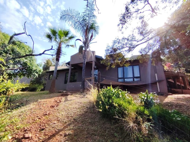 Rear view of the farm property featuring a timber deck, aluminium window frames, and established garden surroundings.