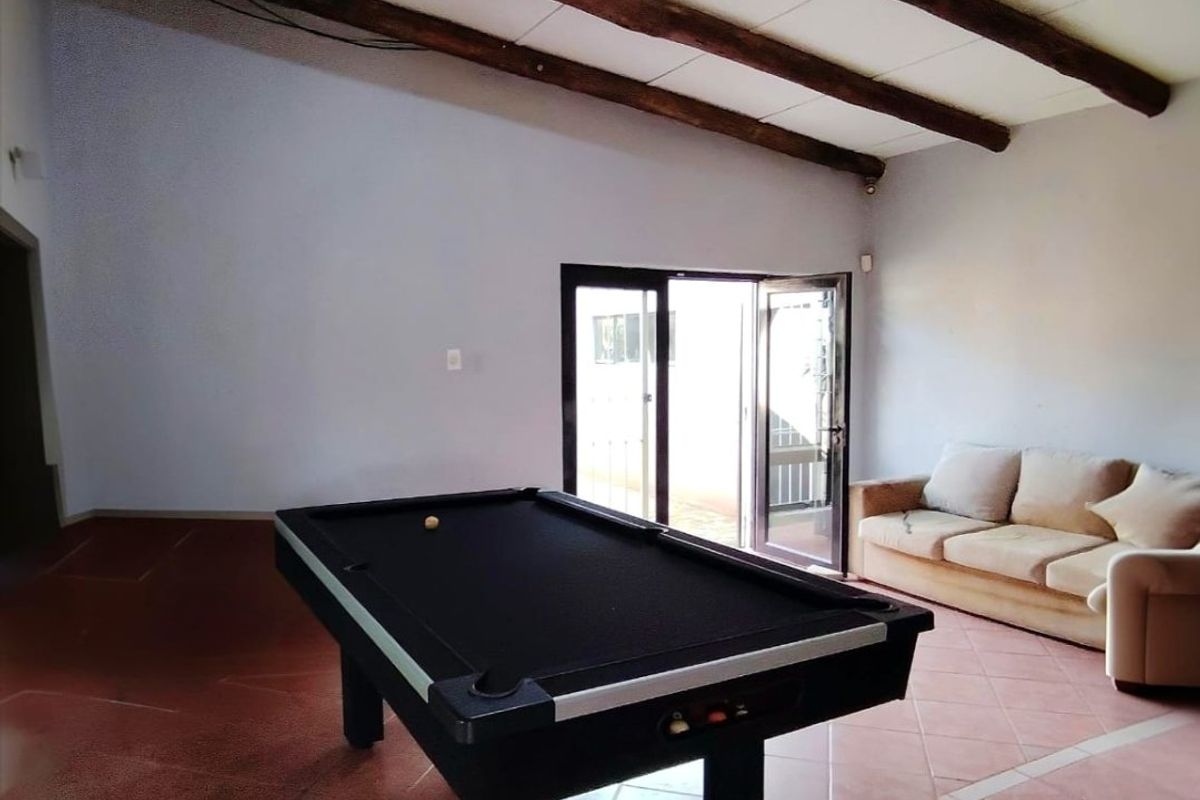 Spacious living area featuring exposed timber ceiling beams, terracotta-style tiled flooring, and direct access to the outdoors through double glass doors.