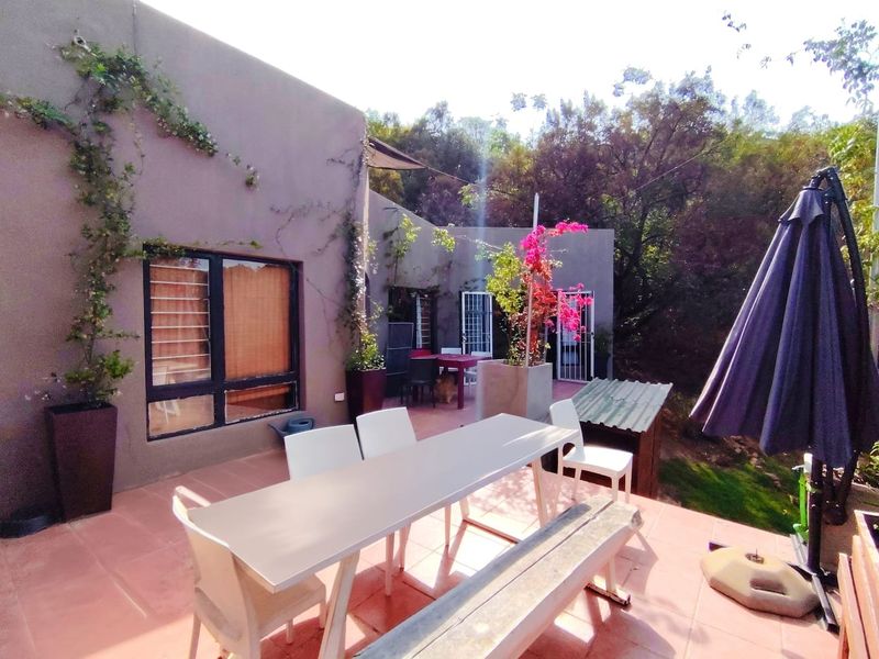 A covered outdoor patio area featuring tiled flooring and direct access to the garden, providing a functional space for outdoor dining and relaxation.
