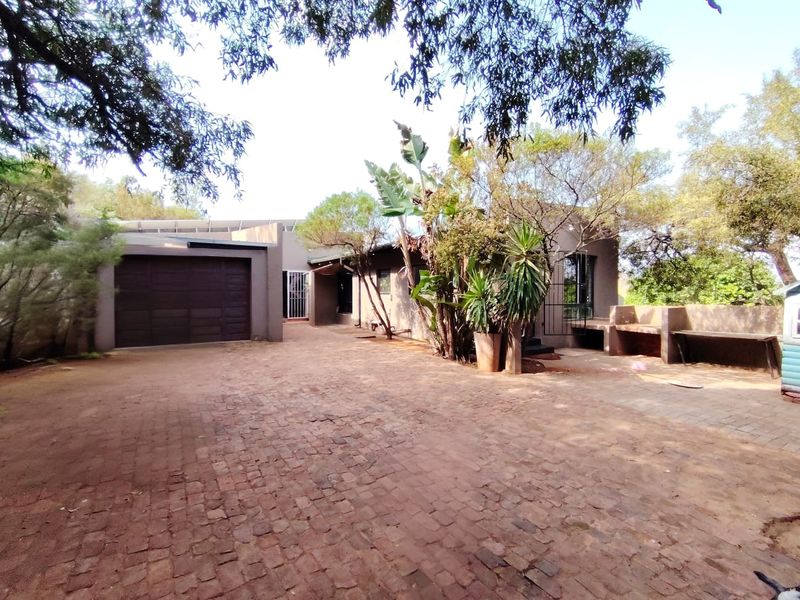 Front exterior view of the farm property featuring a paved driveway, integrated garage, and a built-in outdoor counter area.