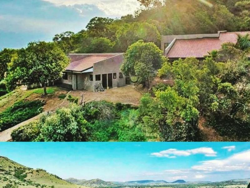 An aerial view of the farm property featuring multiple structures nestled into the hillside, surrounded by extensive natural landscape and mountain views.