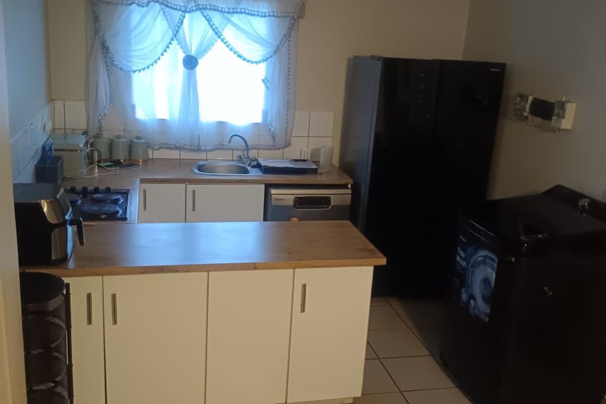 A functional kitchen featuring white cabinetry, laminate countertops, a stainless steel sink, and ceramic tile flooring, providing a practical workspace.