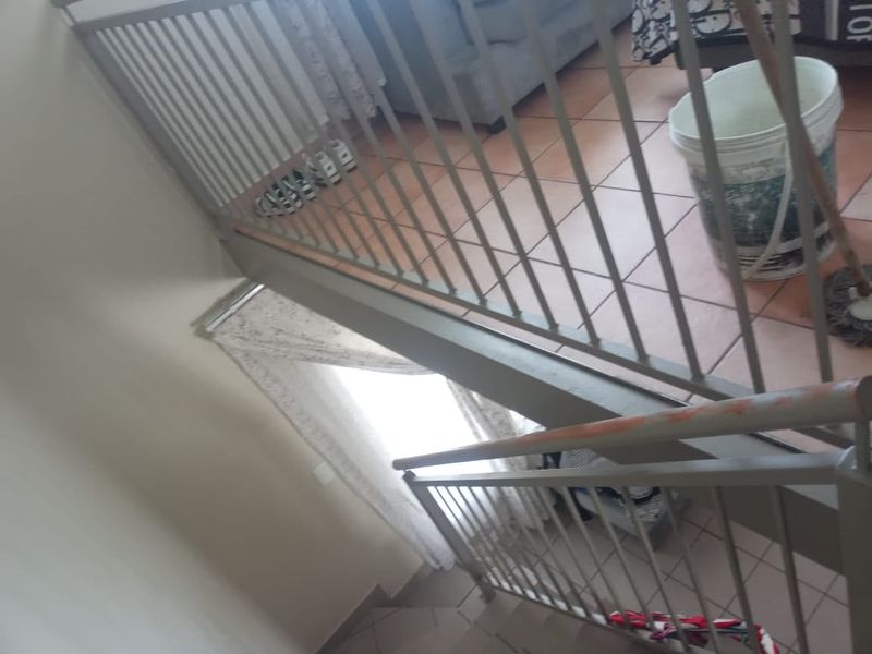 A view looking down a staircase featuring a metal balustrade and tiled flooring.