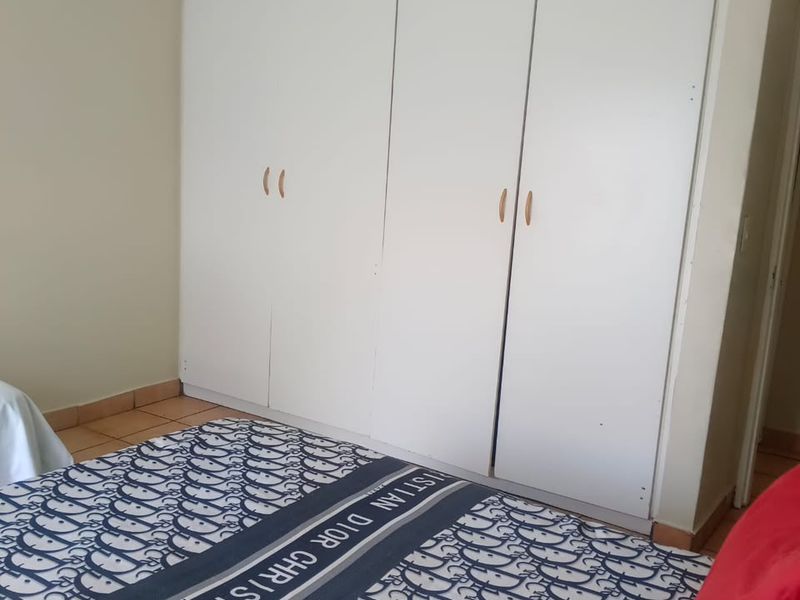 A bedroom featuring white built-in cupboards with simple hardware, providing ample storage space.