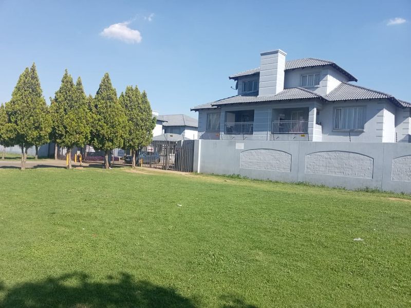 Front exterior view of a two-story residential house featuring a tiled roof, balcony with metal railings, and a secure perimeter wall with electric fencing.
