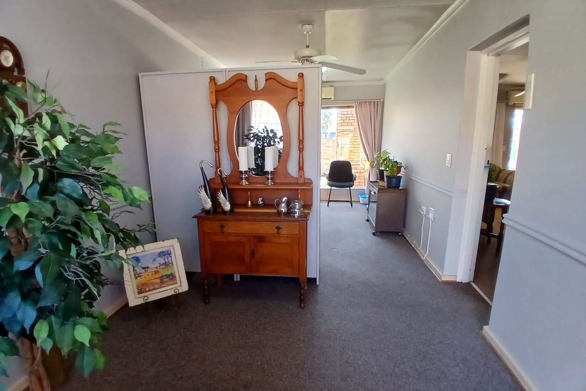 A living area featuring carpeted flooring, a ceiling fan, and classic chair rail molding, providing a neutral base for potential interior updates.