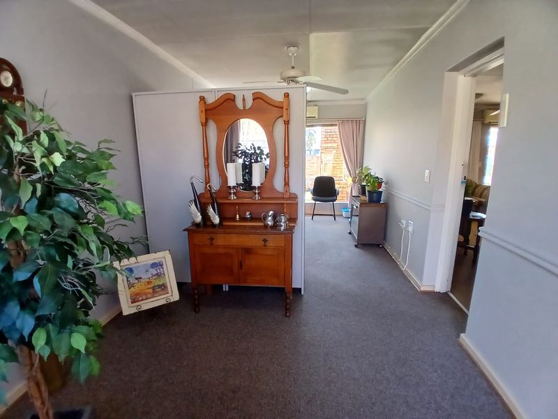 A living area featuring carpeted flooring, a ceiling fan, and classic chair rail molding, providing a neutral base for potential interior updates.