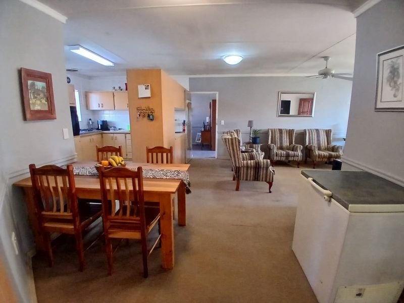 Spacious open-plan living and dining area featuring a functional kitchen layout, neutral wall tones, and carpeted flooring throughout the main living space.