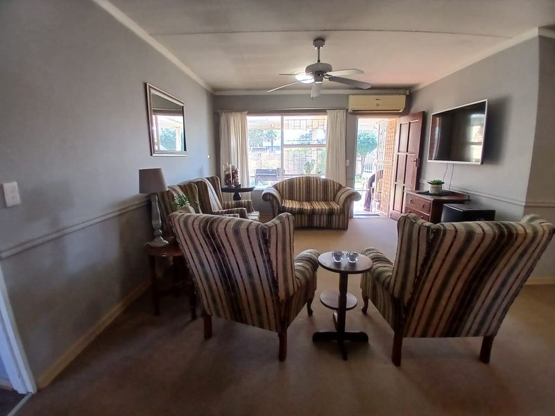 A comfortable living room featuring a ceiling fan, wall-mounted air conditioning, and direct access to the outdoor area through a sliding glass door.