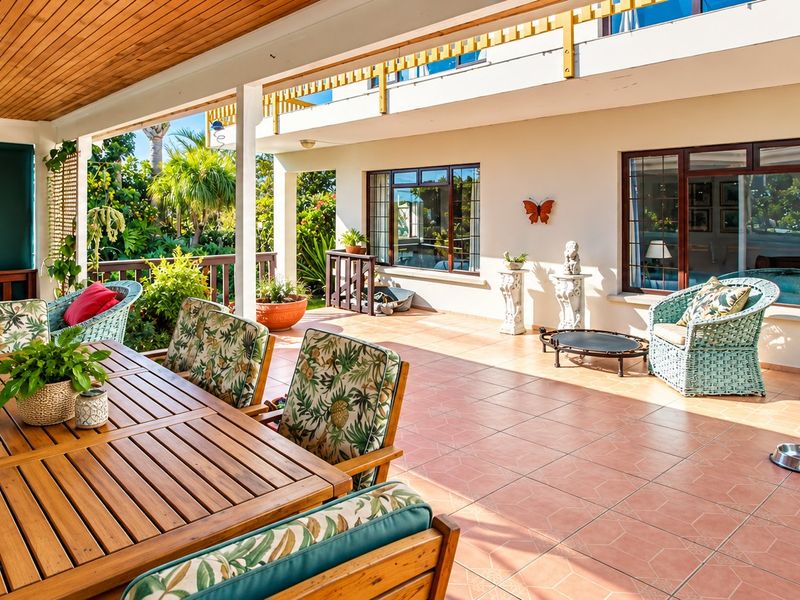 A spacious covered patio featuring tiled flooring, a timber-clad ceiling, and direct access to the home through large windows and sliding glass doors.