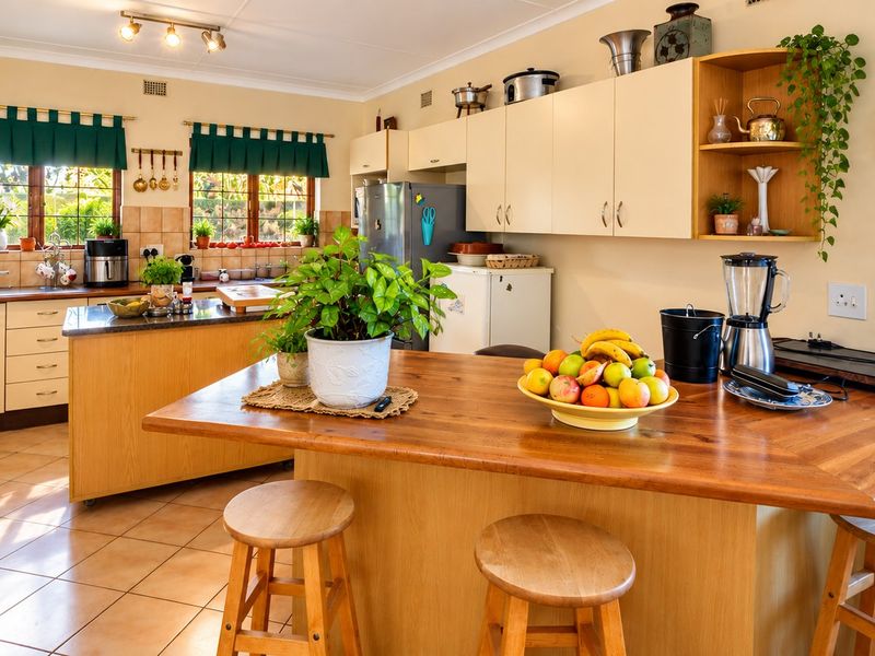 A functional kitchen featuring wooden cabinetry, a central island with breakfast bar seating, tiled flooring, and a tiled backsplash.
