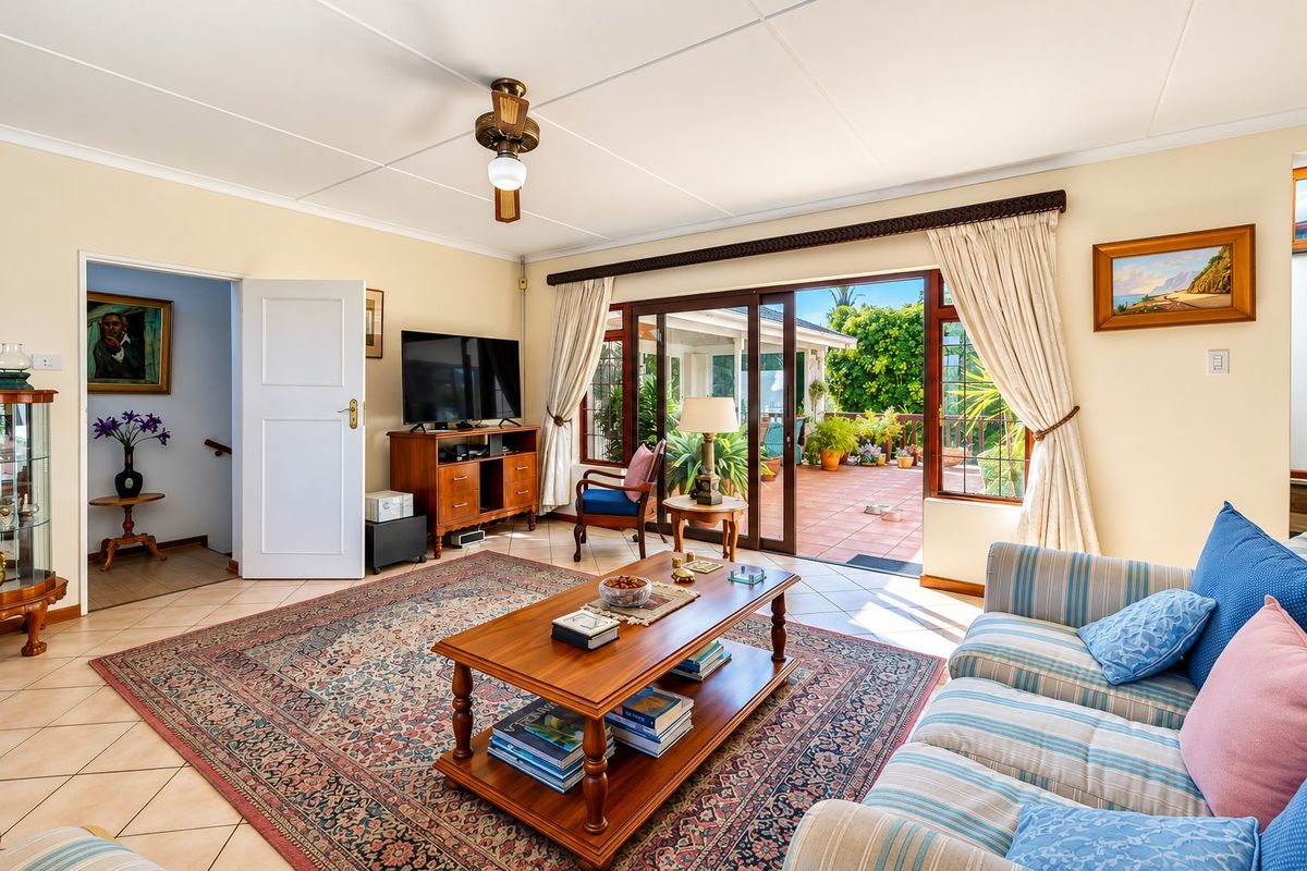 A bright living room featuring tiled floors, a ceiling fan, and large sliding glass doors that provide direct access to an outdoor patio area.